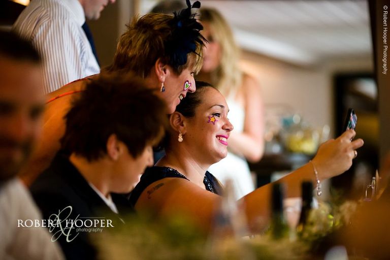 Guests having fun with face stickers at wedding reception at The Stag on the River in Eashing, Surrey