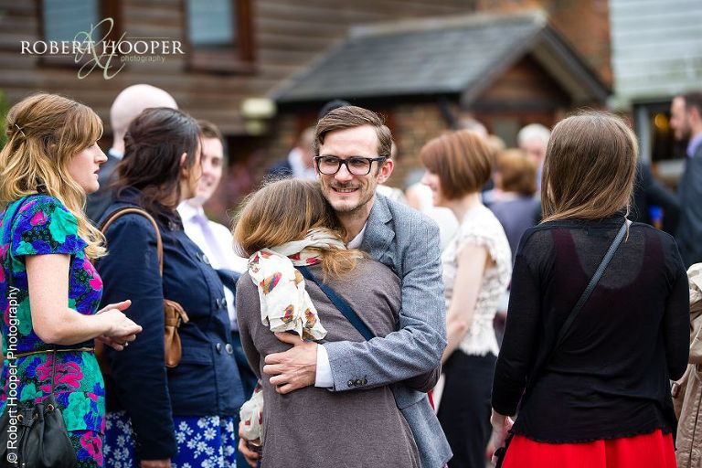 Wedding guests greeting each other as they gather for civil ceremony at Coltsford Mill, Oxted in Surrey