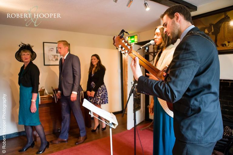 Singer and guitarist playing as guests enter The Mill Room for wedding at Coltsford Mill, Oxted in Surrey