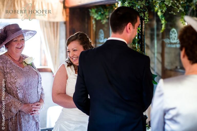 Bride sharing laughter with the guests during marriage ceremony at Coltsford Mill, Oxted in Surrey