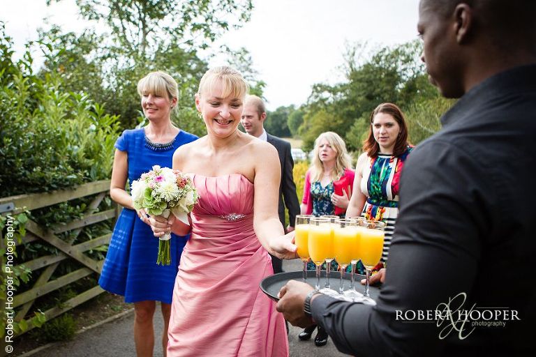 Bridesmaid taking bucks fizz at wedding reception at Coltsford Mill, Oxted in Surrey