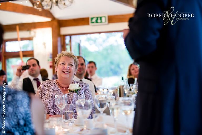 Bride's mum laughing at groom's speech during wedding breakfast at Coltsford Mill, Oxted in Surrey
