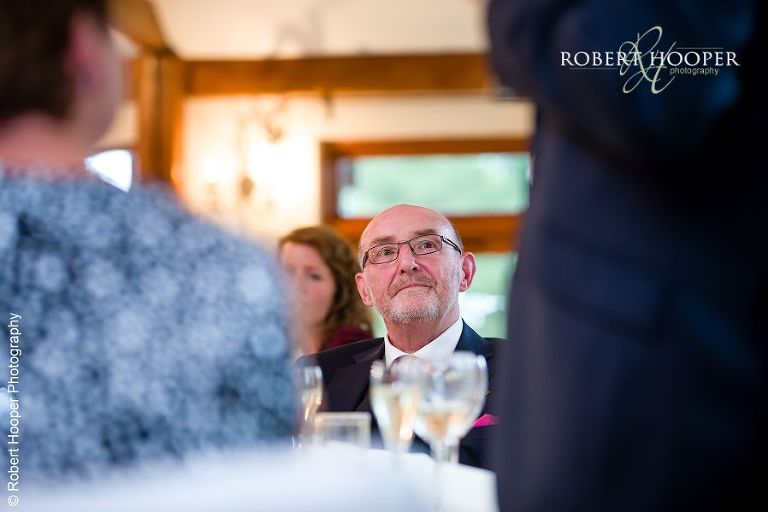 Father of the bride watching groom during his speech at the wedding breakfast at Coltsford Mill, Oxted in Surrey
