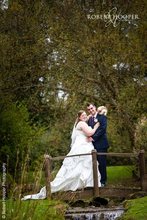 Bride and groom together on little bridge in grounds at Coltsford Mill wedding venue, Oxted in Surrey
