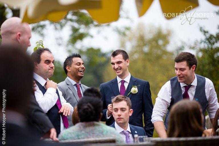 Groom laughing with friends at Spring wedding at Coltsford Mill, Oxted in Surrey