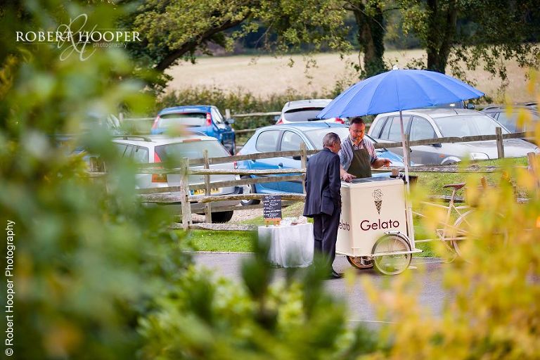 Wedding guest being served an ice cream from a vendor at wedding reception at Coltsford Mill, Oxted in Surrey