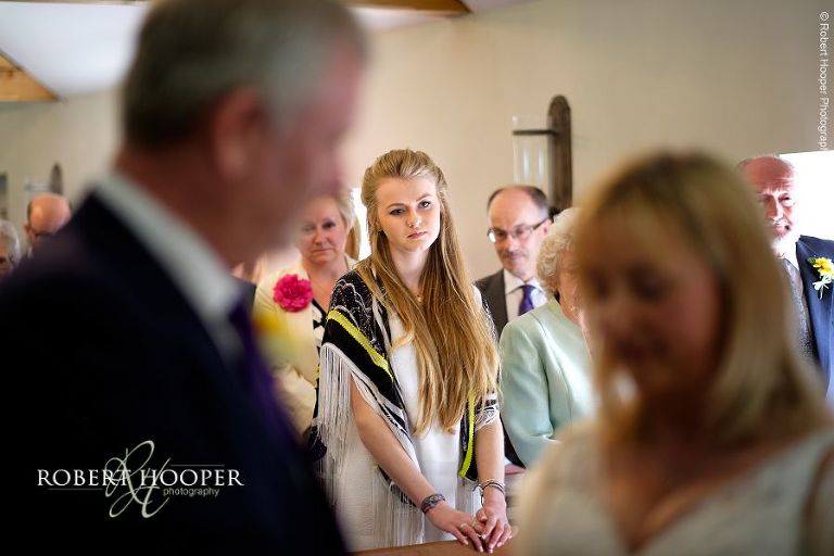 Wedding guest watches on as bride and groom get married at civil wedding ceremony at Oaks Farm Barn, Surrey