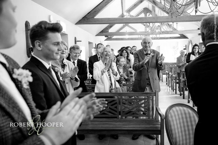 All wedding guests clapping as couple are pronounced man and wife at civil wedding ceremony at Oaks Farm Barn in Surrey