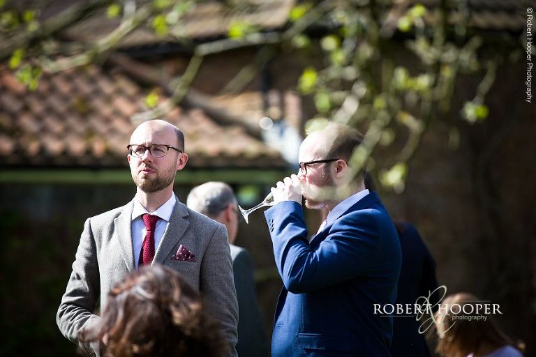 Wedding guests at drinks reception in the gardens of Oaks Farm Barn, Surrey