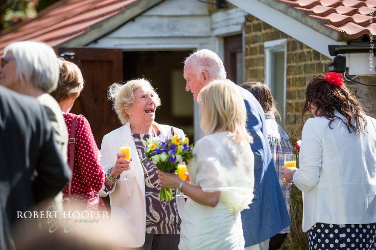 Guests enjoying bucks fizz at drinks and canapes wedding reception at Oaks Farm Barn, Surrey