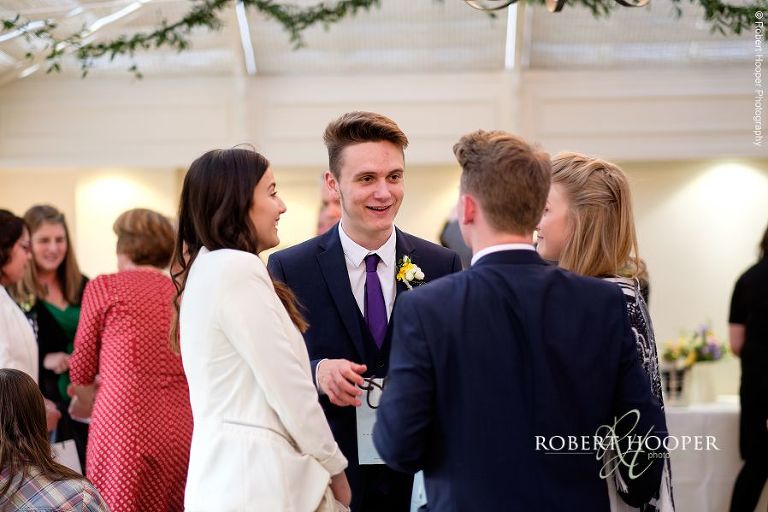 Groomsmen and girlfriends chatting at after dinner drinks on wedding day at Oaks Farm Barn, surrey