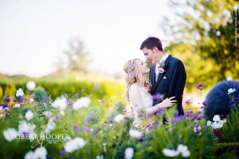 Bride and groom among the wild flowers on their wedding day outside the entrance to the London Golf Club in Kent