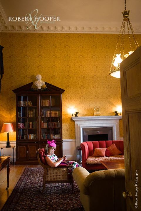 Guest checking her phone whilst waiting for wedding ceremony to commence at Botleys Mansions in Chertsey Surrey