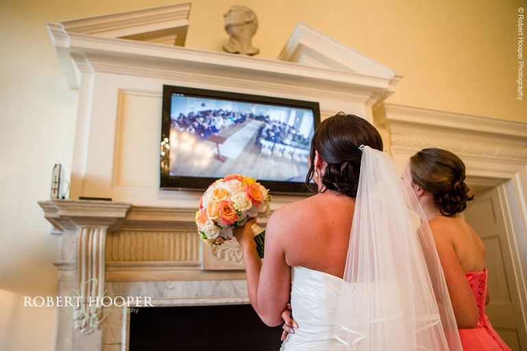 Bride viewing ceremony from video TV in entrance on her wedding day at Botleys Mansions, Chertsey in Surrey