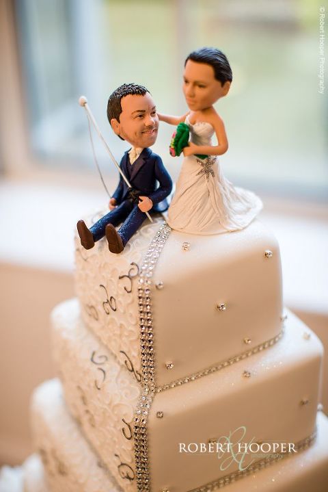 Bride and groom icing figures on top of wedding cake displayed at reception in glass atrium at Botleys Mansion in Surrey