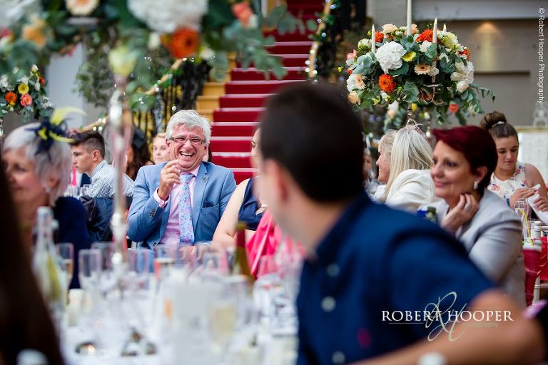 Wedding guests sharing laughter at wedding breakfast in the glass atrium at Botleys Mansion Surrey