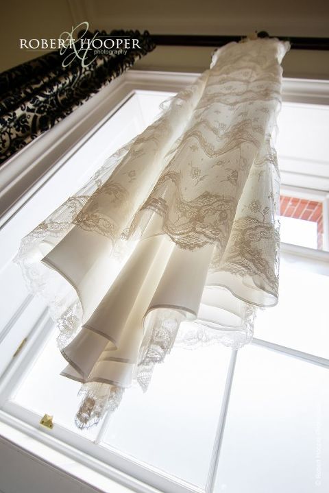 Full length picture of wedding dress hanging on curtain rail so as not to crease ready for bride to wear on her wedding day at Botleys Mansion Chertsey Surrey