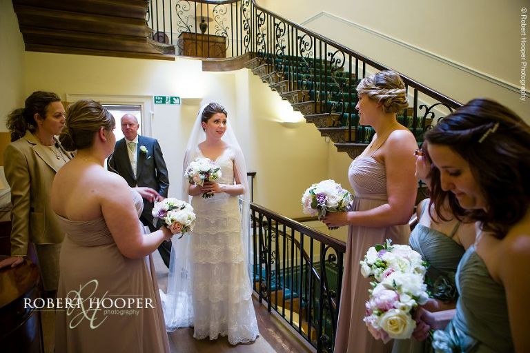 Bride with bridesmaids waiting to go down to ceremony room on hr wedding day at Botleys Mansion Surrey