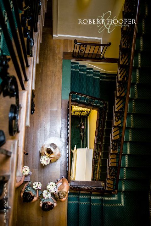 Birds eye view of bride and bridemaids waiting to go down to ceremony room for marriage at Botleys Mansion Surrey
