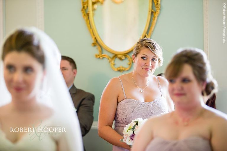 Bridesmaid smiling during bride and groom vows at civil wedding ceremony in the Green Room Botleys Mansion Surrey