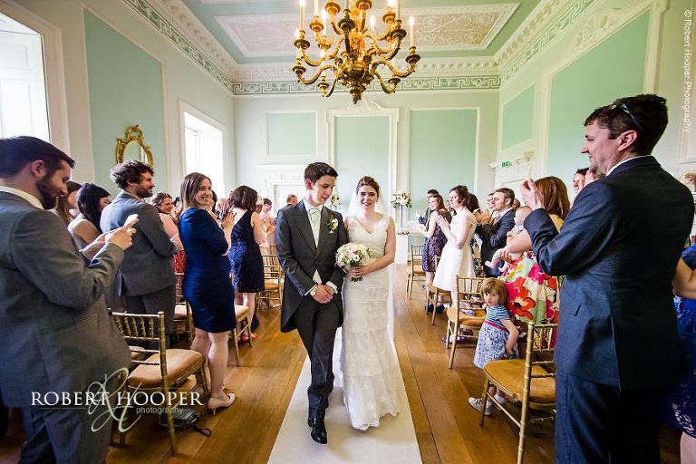 Bride and groom coming back up the isle as man and wife after their civil wedding ceremony in the Green Room at Botleys Mansion