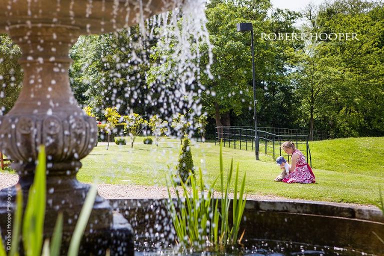 Wedding guest amusing her toddler on the grass in fore court at Botleys Mansion Surrey