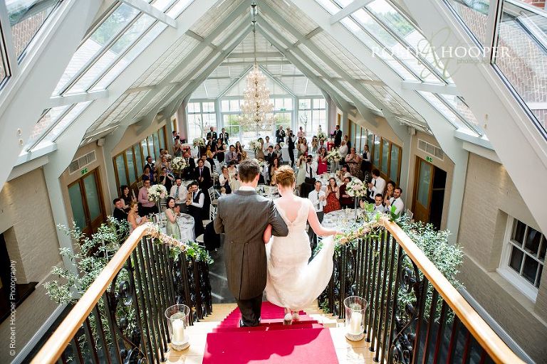 Bride and groom make their grand entrance down the red carpeted stairs of The Atrium at Botleys Mansion Chertsey Surrey