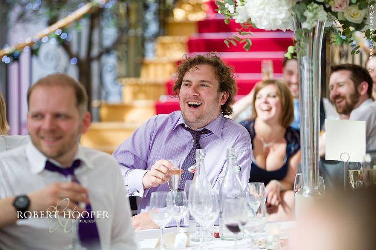 Guests laughing and enjoying the speeches at wedding breakfast in The Atrium at Botleys Mansion Surrey