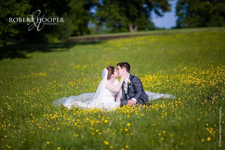 Bride and groom kiss in the buttercups in the grounds of Botleys Mansion Surrey