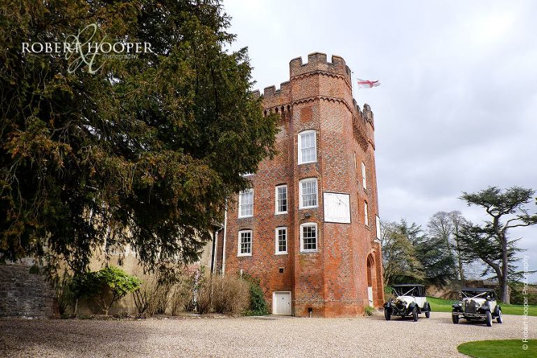 2 vintage cars waiting outside Farnham Castle to take bride to St Anne's Church on her wedding day