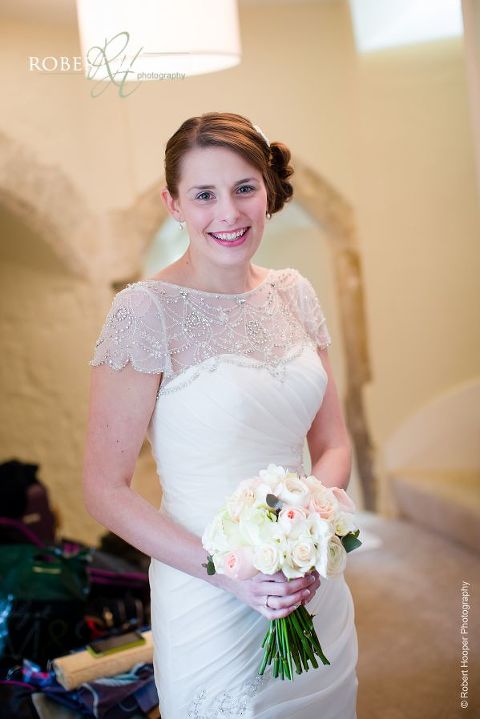 Bride holding bouquet of roses taken just after bridal preps before departing for St. Anne's Church from Farnham Castle Surrey