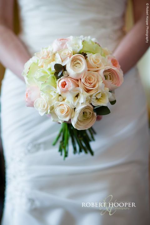 Bouquet of roses in creams, pinks and peach held by a bride on her wedding day at Farnham Castle Surrey