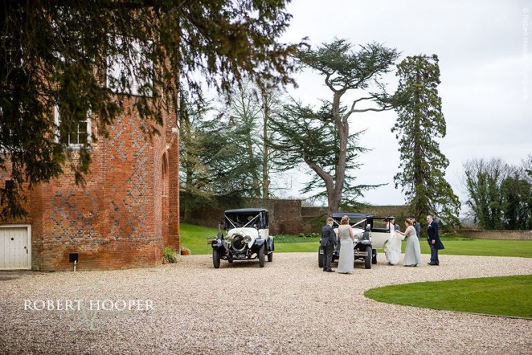 Brides and bridesmaids getting into vintage wedding cars outside Farnham Castle on their way to St. Anne's Church Surrey for marriage ceremony