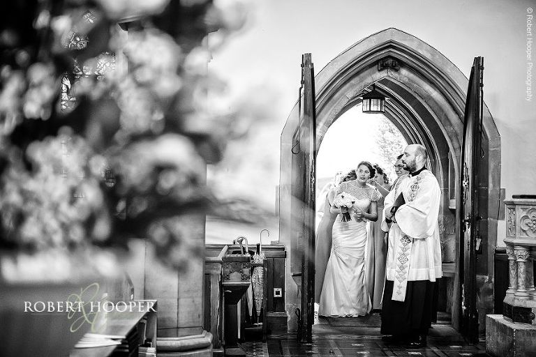 Bride waiting at the church doors to walk down the isle on her wedding day at St. Anne's Church in Surrey