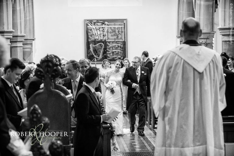 Bride gives her groom big smile as she walks down the isle on their wedding day at St Anne's Church and Farnham Castle Surrey