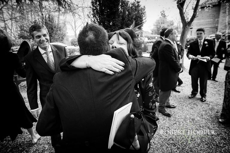 Groom hugs wedding guest after wedding service outside St Anne's Church Surrey