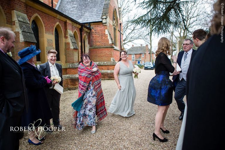 Wedding guest wrapped in tartan blanket on a chilly wedding day at St. Anne's Church Surrey