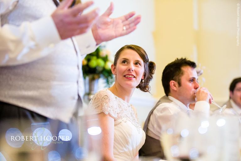 Bride listening during her dad's speech at wedding breakfast Farnham Castle Surrey