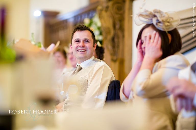 Best man laughing at best man speech during wedding breakfast at Farnham Castle Surrey