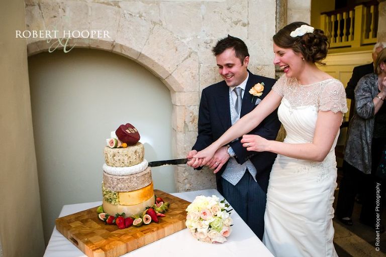Bride and groom cutting their cheese cake before the first dance on their wedding day at Farnham Castle Surrey