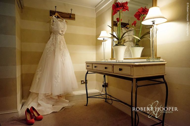 Bride's dress hanging in the hallway in preparation for wedding day at All Saints' Hordle Church Hampshire and The Three Tuns, Dorset