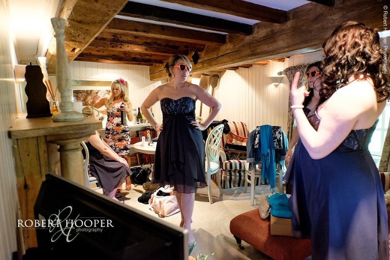 Bridesmaids wearing love heart sunglasses during bridal preparations for wedding day at All Saints' Hordle Church Hampshire and The Three Tuns, Dorset