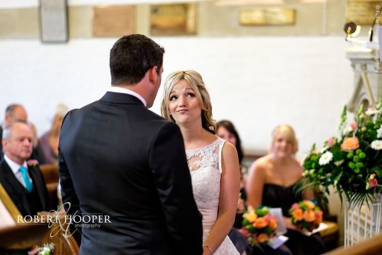 Bride pulling funny face during her vows on her wedding day at All Saints' Hordle Church Hampshire