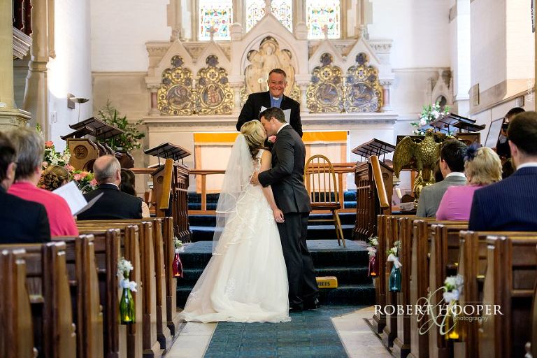Bride and bride groom kiss after their vows on their wedding day at All Saints' Church Hordle Hampshire