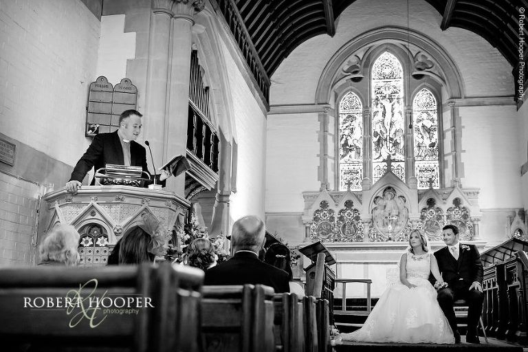 Black and white image of Vicar in pulpit reading a sermon during wedding ceremony at All Saints' Church Hordle