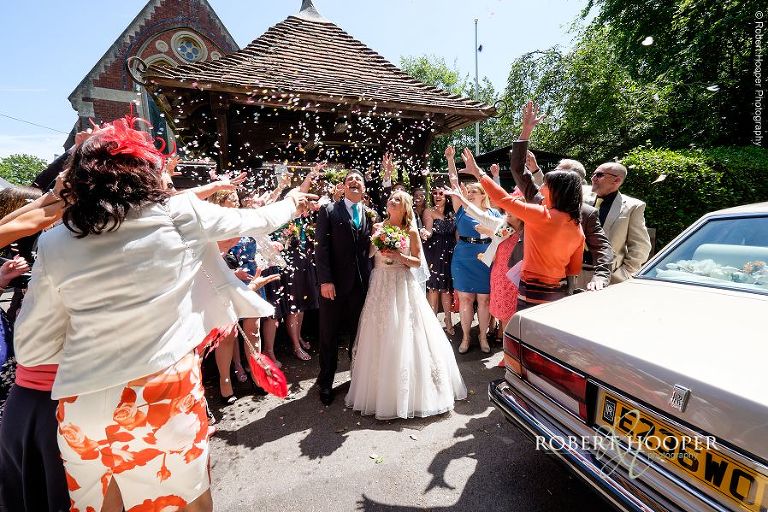 Wedding guests throwing lots of confetti over bride and groom at the lychgate after their marriage ceremony at All Saints' Church Hordle Hampshire