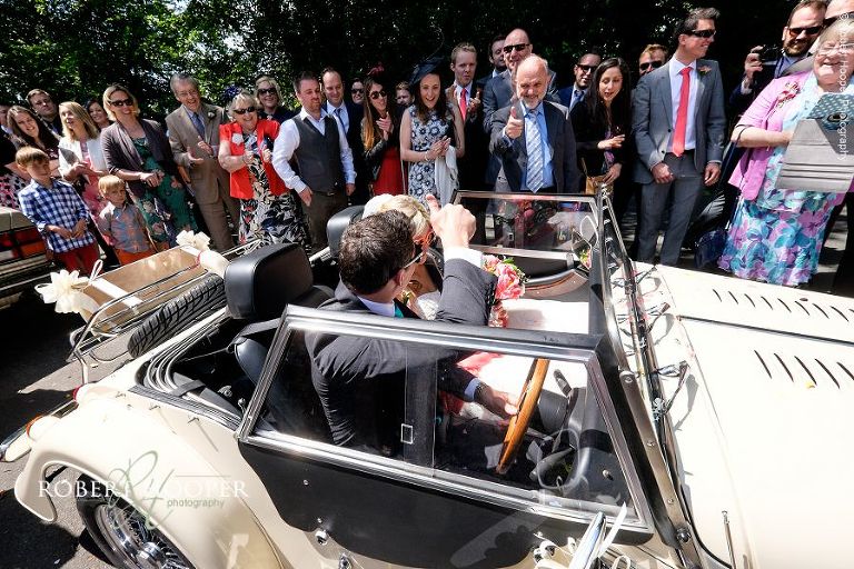 Groom gives wedding guest the "thumbs up" as he drives off after just getting married at All Saints Hordle Hampshire