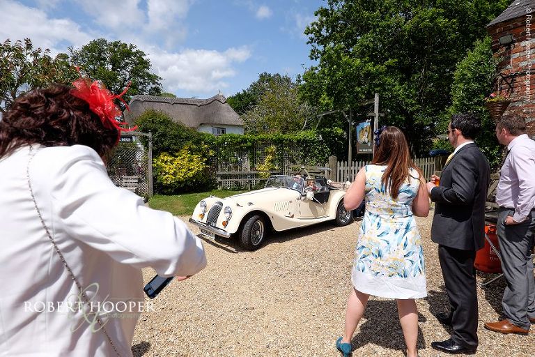 Bride and groom arrive at The Three Tuns for their wedding reception in cream vintage wedding car after a drive through the New Forest as newlyweds