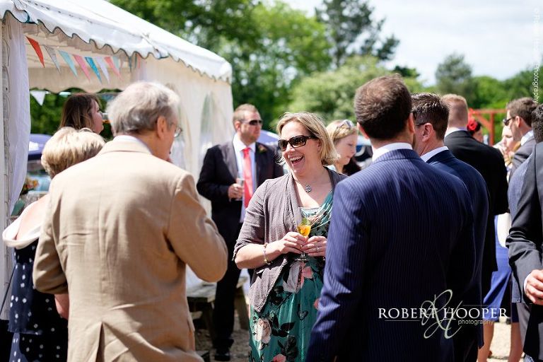 Wedding guests enjoying pimms and sunshine at summer wedding reception in the marquee / barn at The Three Tuns Bransgore, Dorset