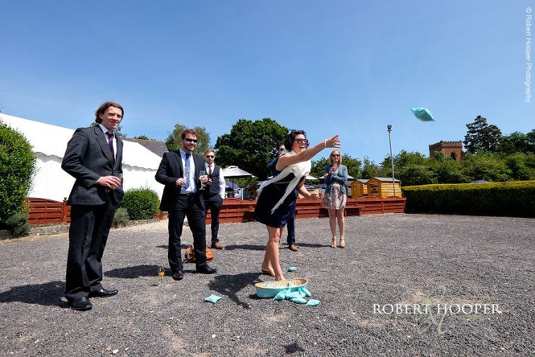 Wedding guests play cornhole bean bag toss game at wedding reception in held in the marquee at The Three Tuns Bransgore, Dorset